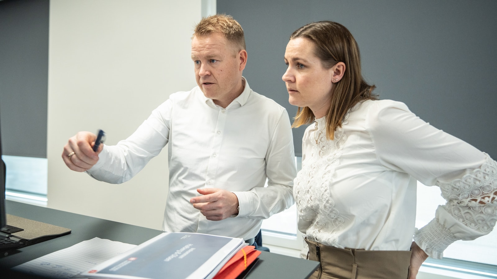 To kollegaer står og kigger på noget arbejde sammen